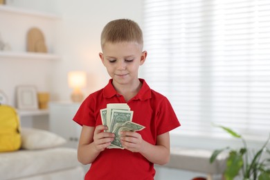 Photo of Little boy holding pocket money at home