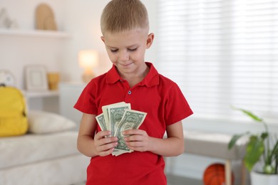 Photo of Little boy holding pocket money at home