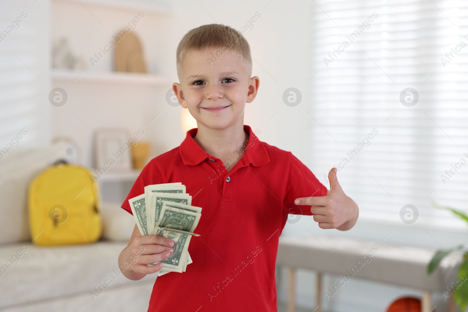 Photo of Little boy holding pocket money at home