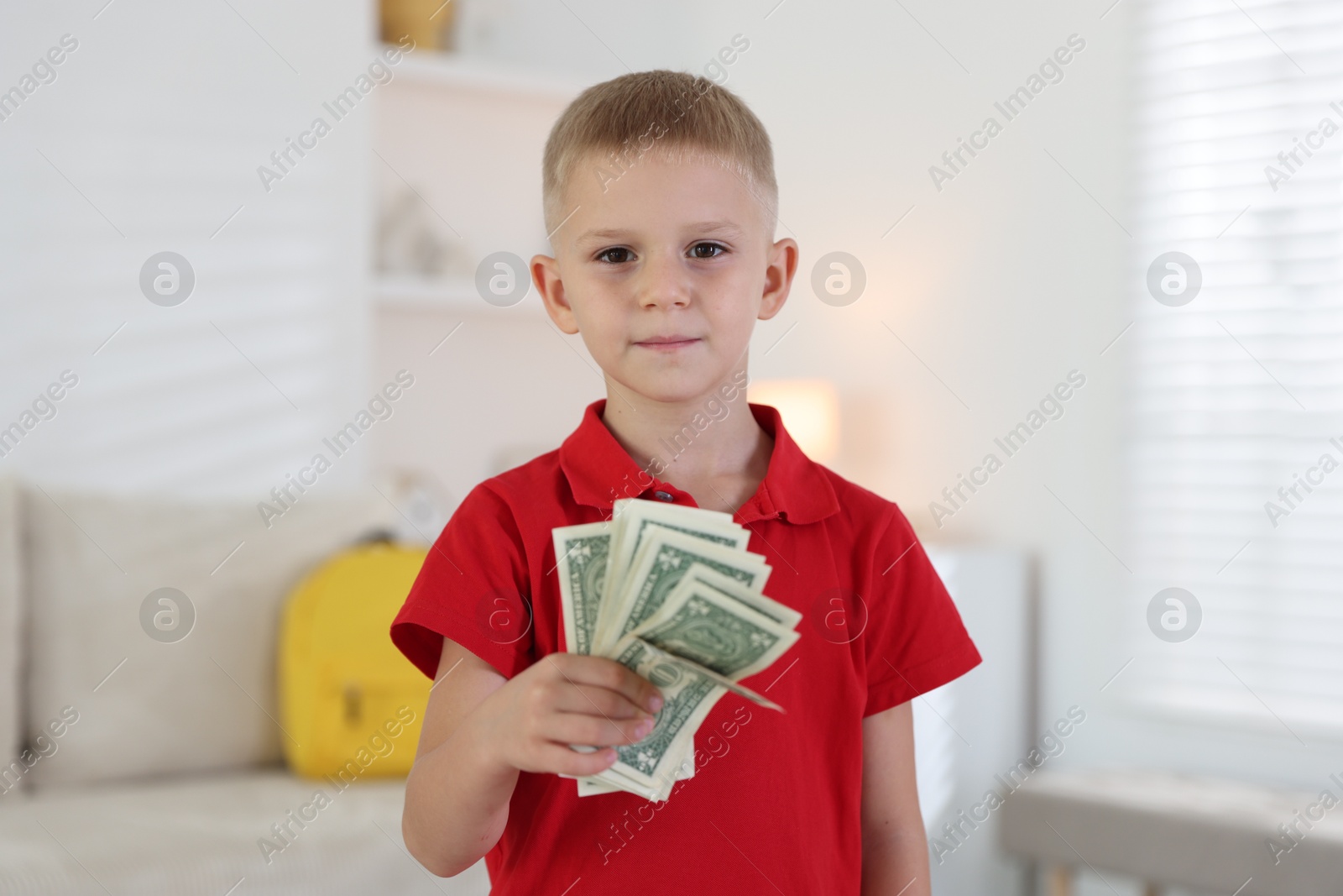 Photo of Little boy holding pocket money at home