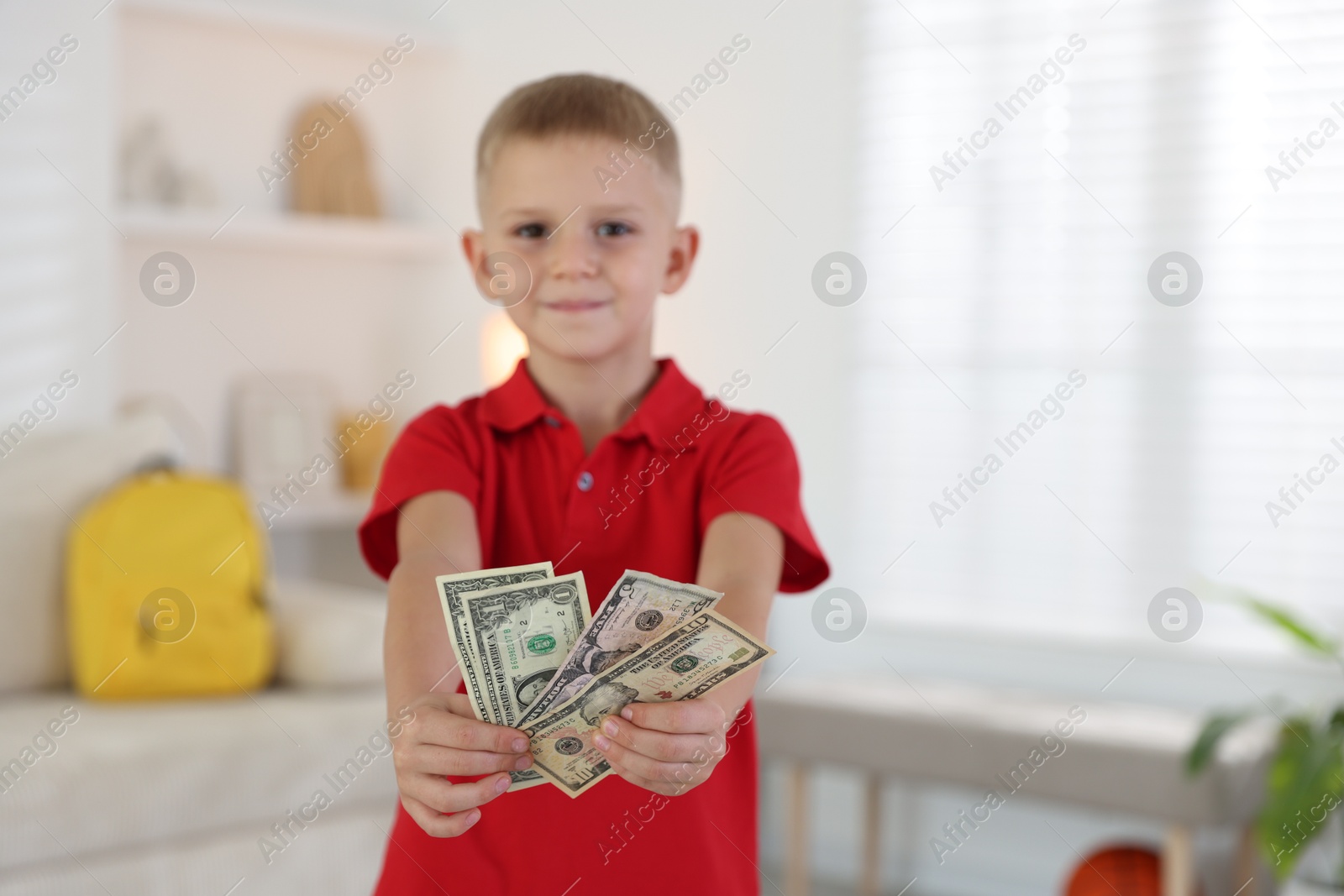 Photo of Little boy holding pocket money at home, selective focus