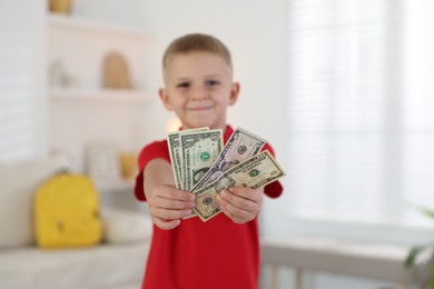 Photo of Little boy holding pocket money at home, selective focus