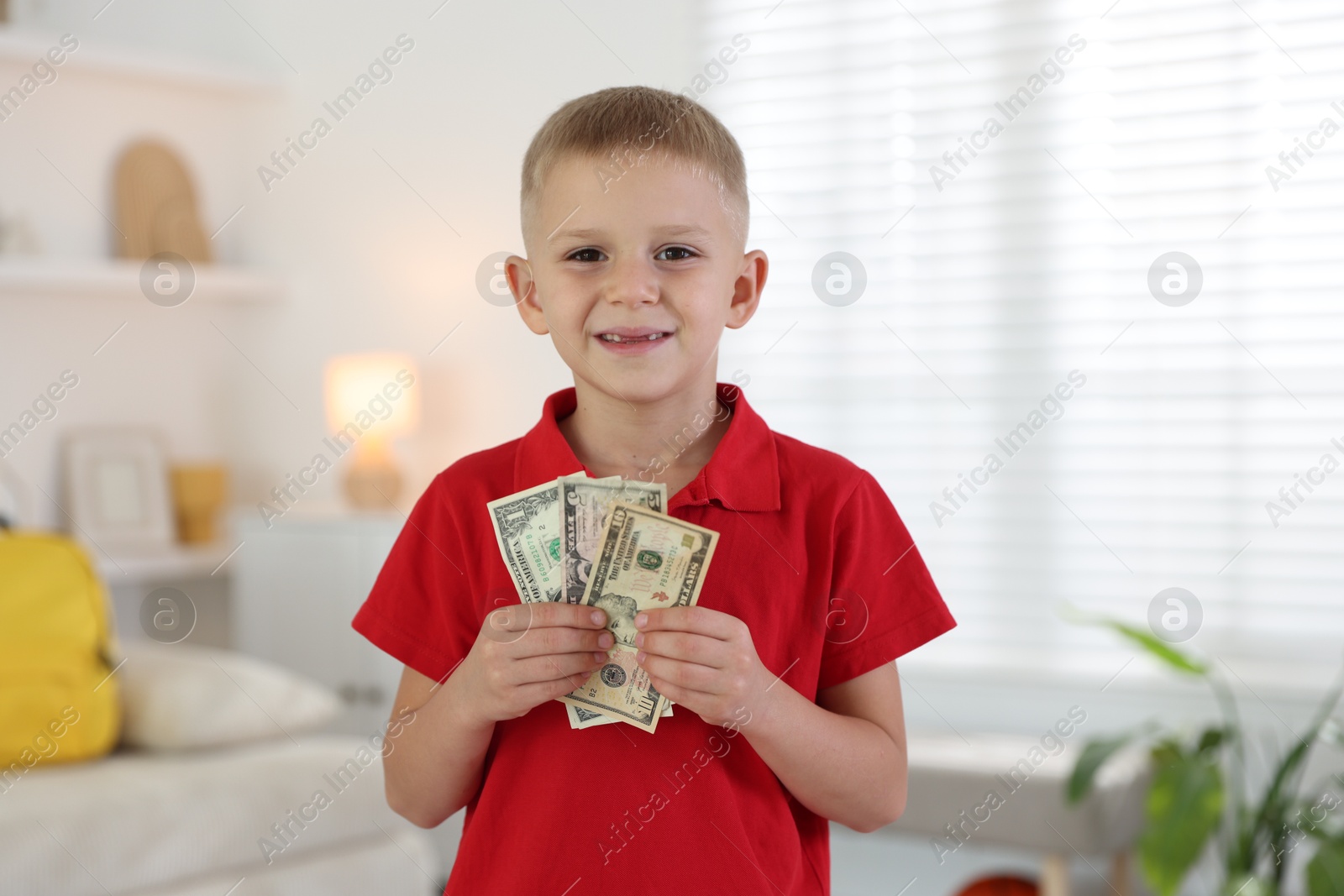 Photo of Little boy holding pocket money at home