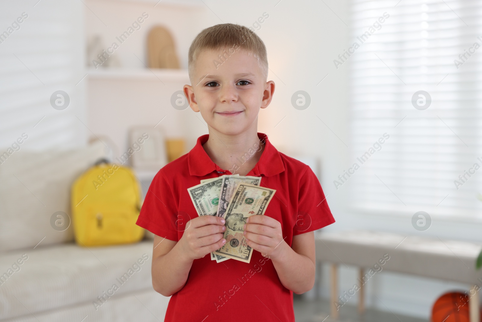 Photo of Little boy holding pocket money at home