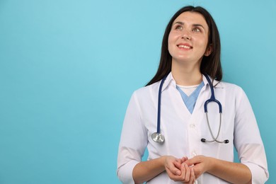 Photo of Portrait of nurse with stethoscope on light blue background, space for text