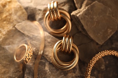 Photo of Different stylish gold jewelry in smoke on rocks, closeup