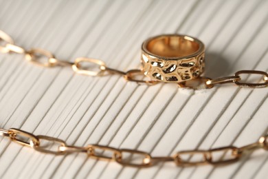 Photo of Stylish gold necklace and ring on sand, closeup