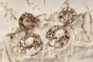 Photo of Stylish gold earrings on sand, top view
