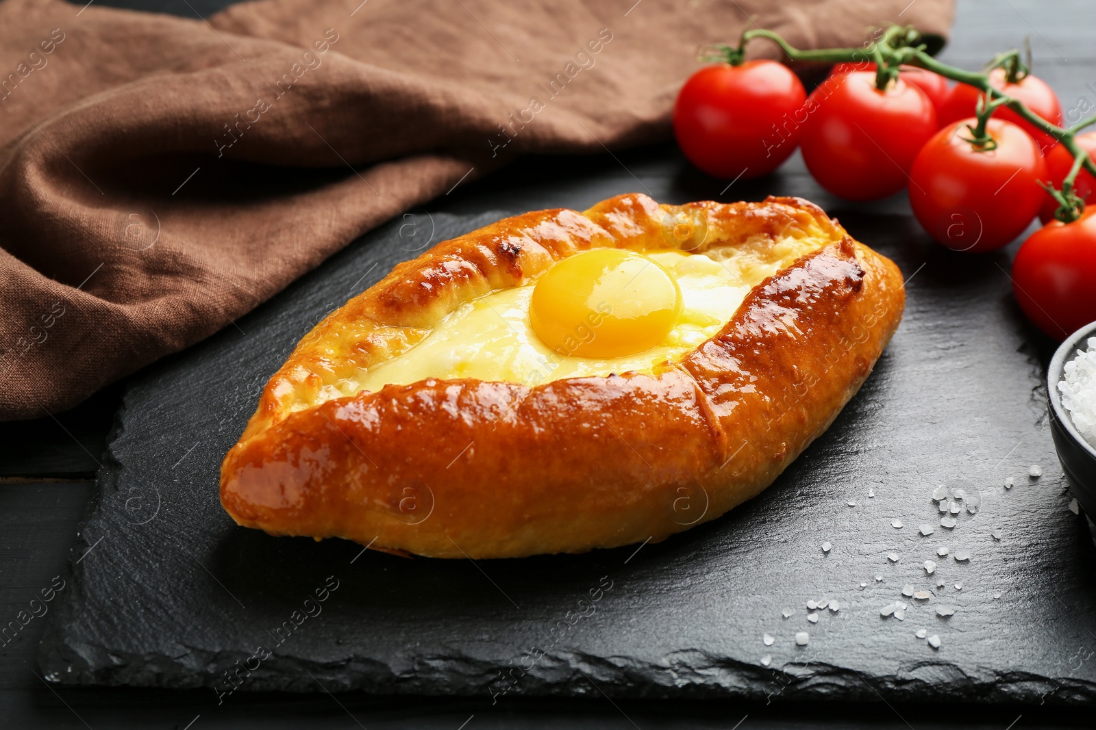 Photo of Tasty khachapuri with cheese and egg on black table, closeup