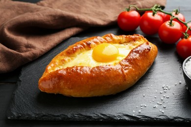 Photo of Tasty khachapuri with cheese and egg on black table, closeup
