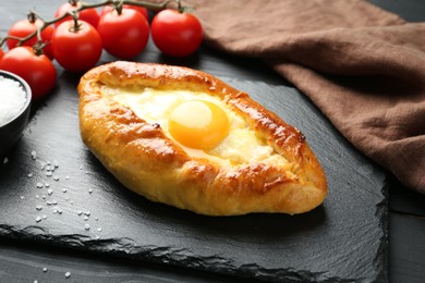 Photo of Tasty khachapuri with cheese and egg on black table, closeup