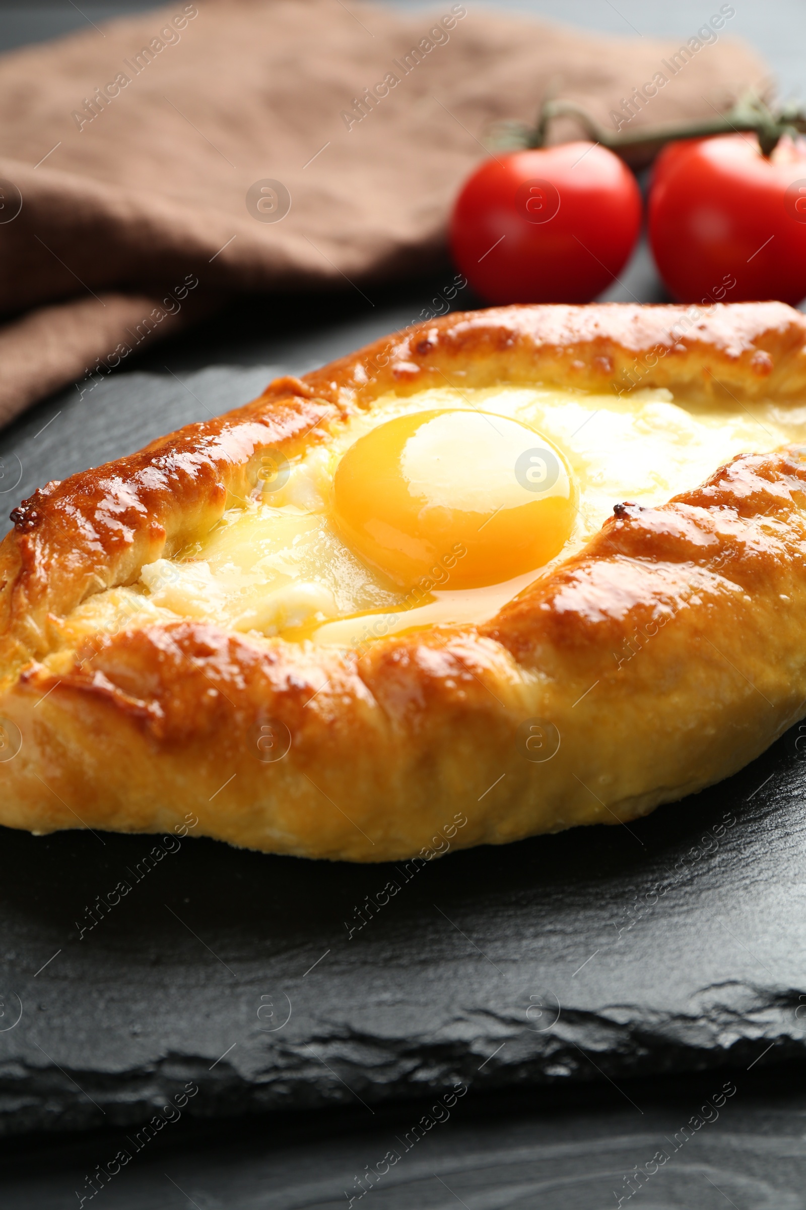 Photo of Tasty khachapuri with cheese and egg on black table, closeup