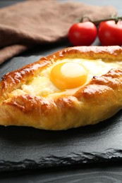 Photo of Tasty khachapuri with cheese and egg on black table, closeup
