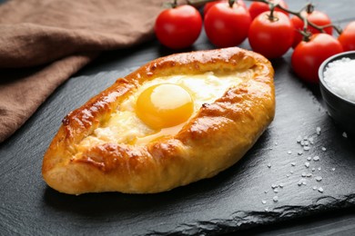 Photo of Tasty khachapuri with cheese and egg on black table, closeup