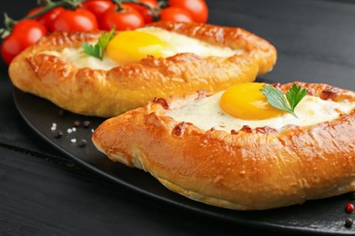 Photo of Tasty khachapuri with cheese and eggs on black table, closeup