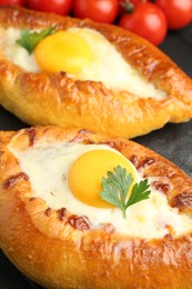 Photo of Tasty khachapuri with cheese and eggs on black table, closeup