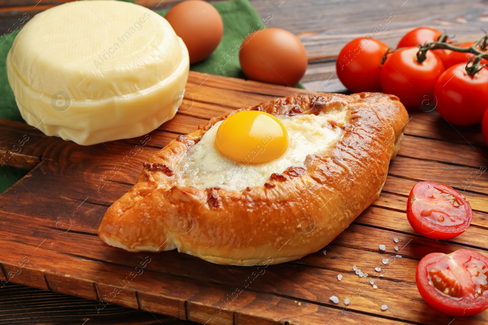 Photo of Tasty khachapuri with cheese and other products on wooden table, closeup