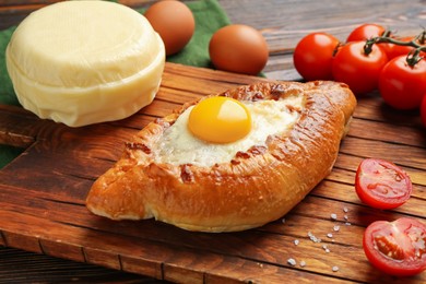 Photo of Tasty khachapuri with cheese and other products on wooden table, closeup