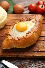 Photo of Tasty khachapuri with cheese and other products on wooden table, closeup
