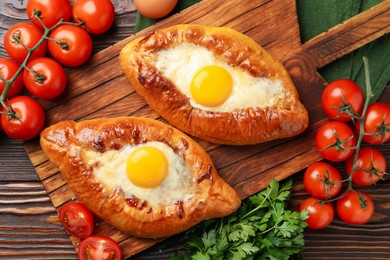 Photo of Tasty khachapuri with cheese, eggs and other products on wooden table, flat lay