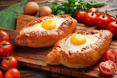 Photo of Tasty khachapuri with cheese, eggs and other products on wooden table, closeup