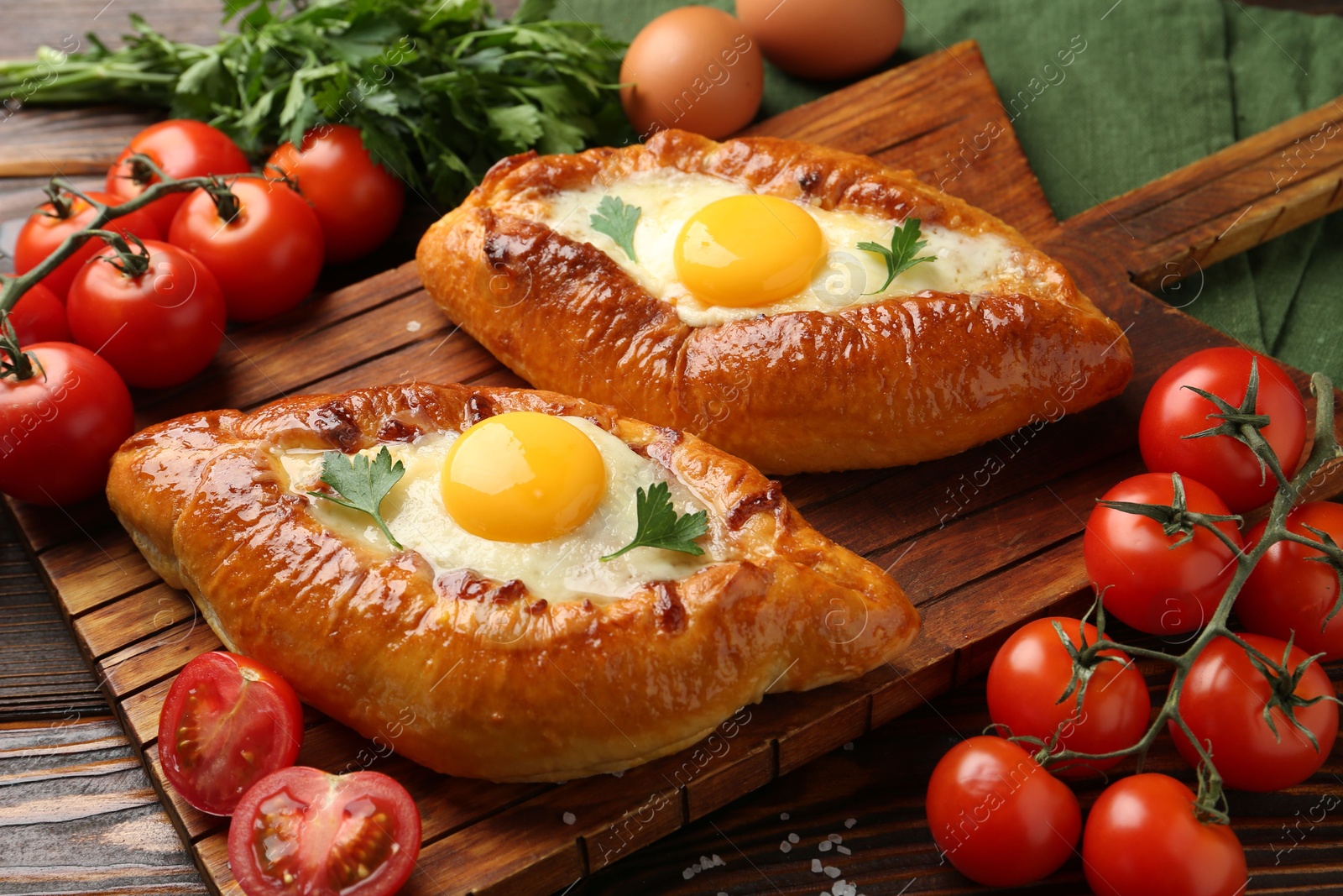 Photo of Tasty khachapuri with cheese, eggs and other products on wooden table, closeup