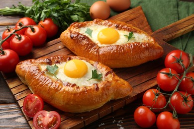 Photo of Tasty khachapuri with cheese, eggs and other products on wooden table, closeup