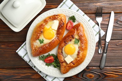 Photo of Tasty khachapuri with cheese and eggs served on wooden table, flat lay