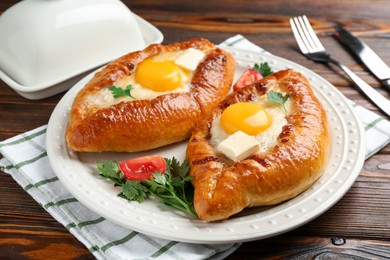 Photo of Tasty khachapuri with cheese and eggs served on wooden table, closeup