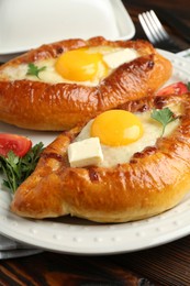Photo of Tasty khachapuri with cheese and eggs served on wooden table, closeup