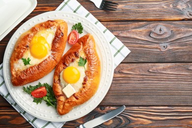 Photo of Tasty khachapuri with cheese and eggs served on wooden table, flat lay. Space for text