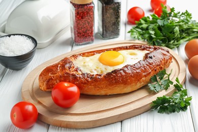 Photo of Tasty khachapuri with cheese, eggs and other products on white wooden table, closeup