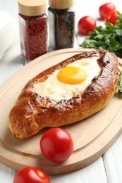 Photo of Tasty khachapuri with cheese, egg and other products on white wooden table, closeup