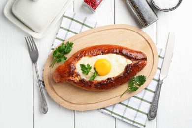 Photo of Tasty khachapuri with cheese and egg served on white wooden table, flat lay