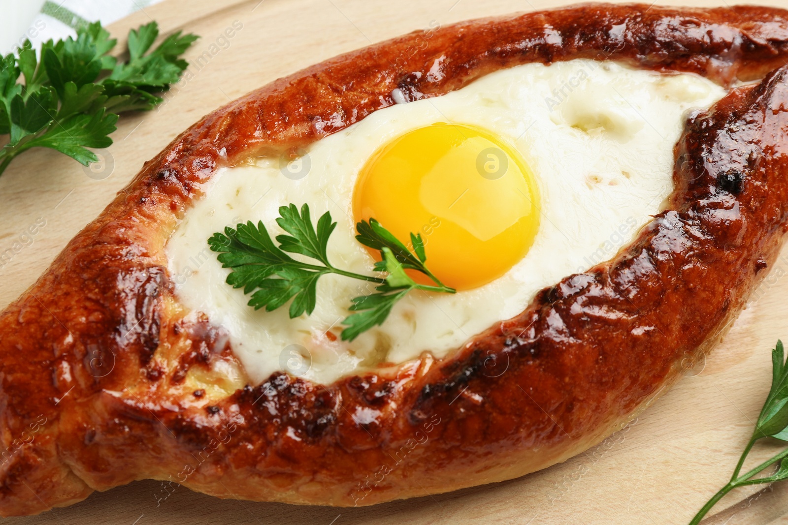 Photo of Tasty khachapuri with cheese, egg and parsley on table, closeup