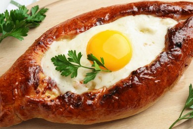 Photo of Tasty khachapuri with cheese, egg and parsley on table, closeup