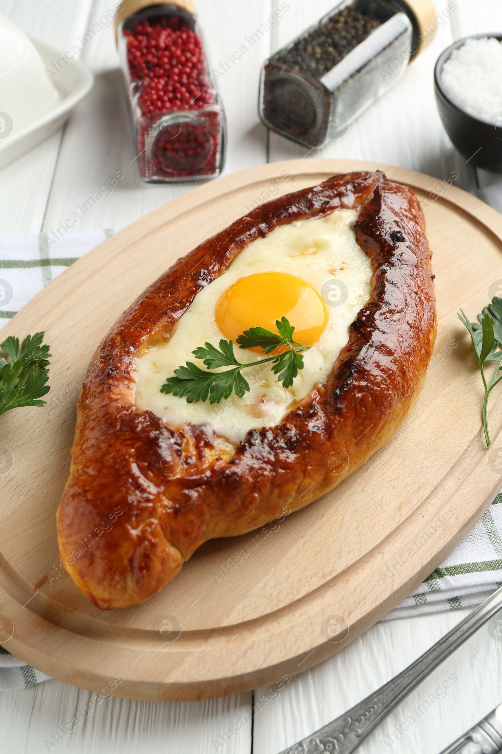 Photo of Tasty khachapuri with cheese, egg and spices on white wooden table