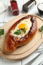 Photo of Tasty khachapuri with cheese, egg and spices on white wooden table