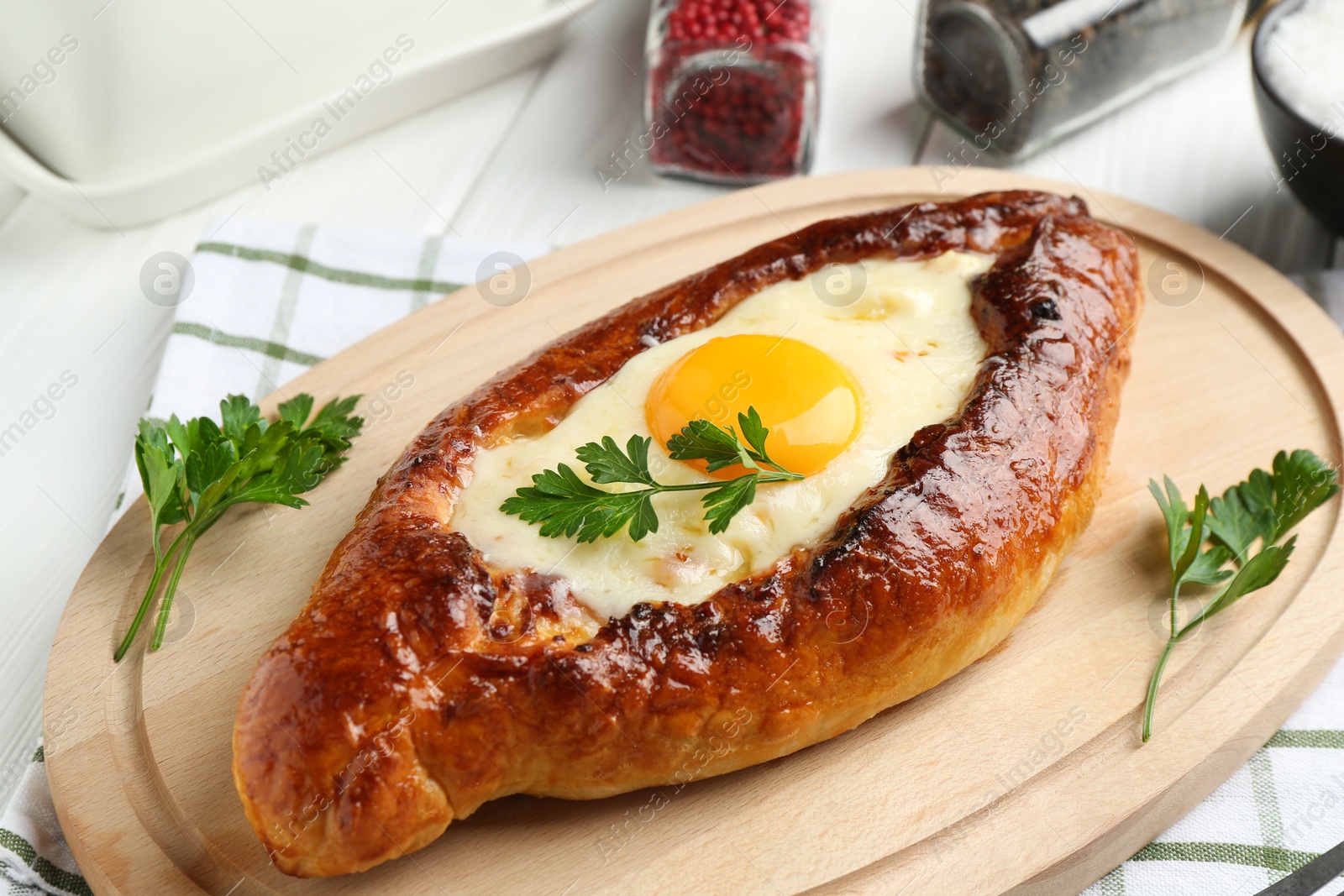 Photo of Tasty khachapuri with cheese, egg and spices on white wooden table, closeup