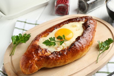 Photo of Tasty khachapuri with cheese, egg and spices on white wooden table, closeup