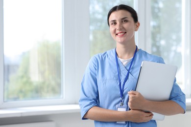 Photo of Nurse with laptop near window in clinic, space for text