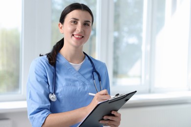 Photo of Nurse with clipboard taking notes near window in clinic, space for text