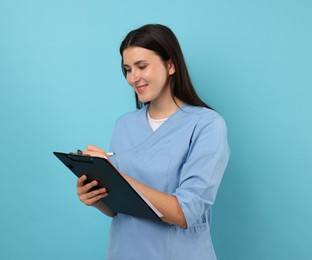Photo of Nurse with clipboard taking notes on light blue background