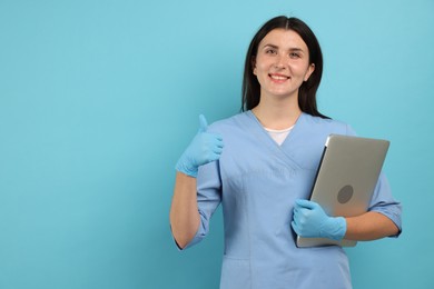 Photo of Nurse with laptop showing thumbs up on light blue background, space for text