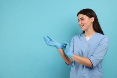Photo of Nurse in uniform wearing gloves on light blue background, space for text