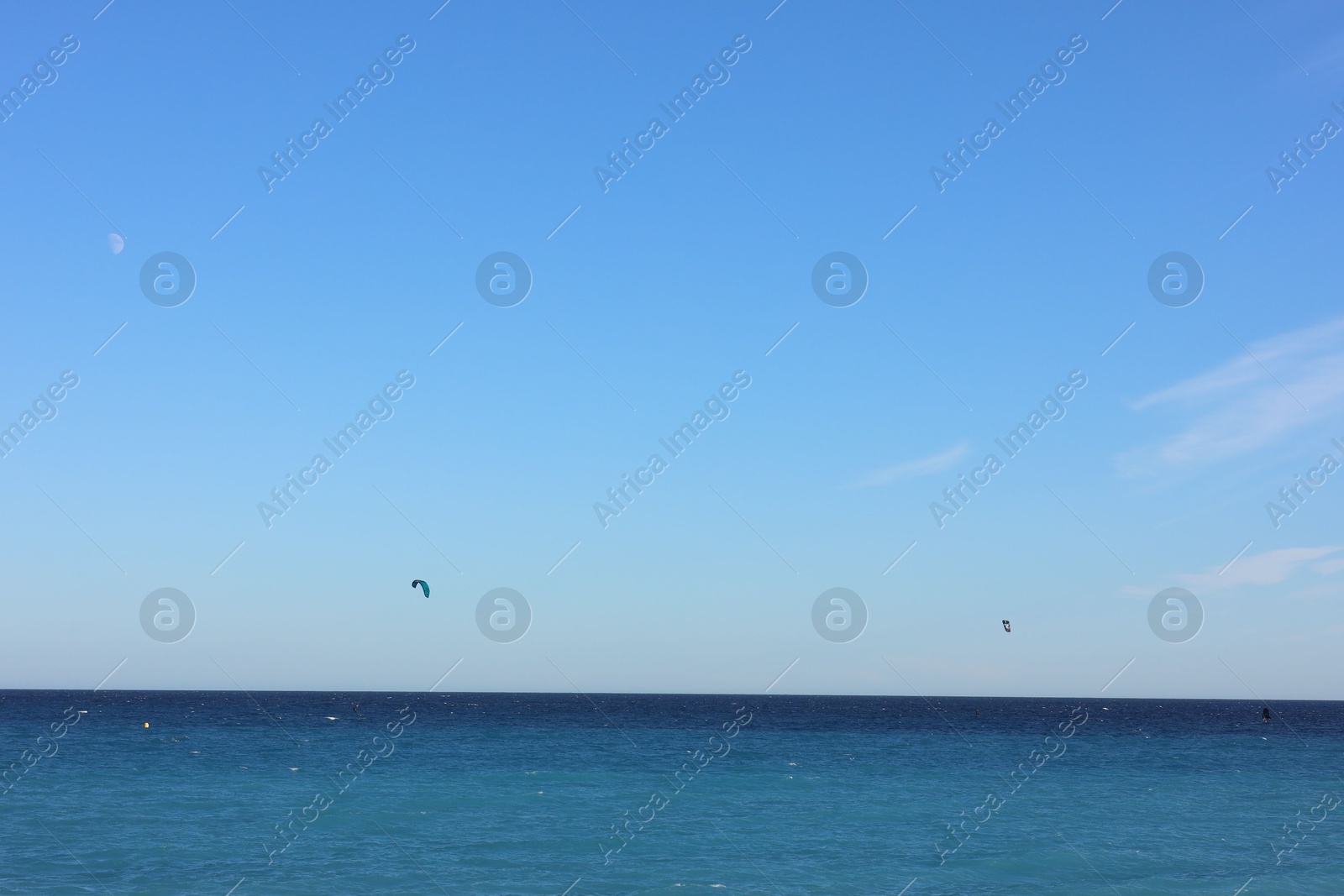 Photo of Beautiful view of wavy sea and people parasailing on sunny day