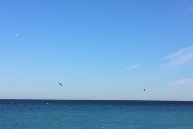 Photo of Beautiful view of wavy sea and people parasailing on sunny day