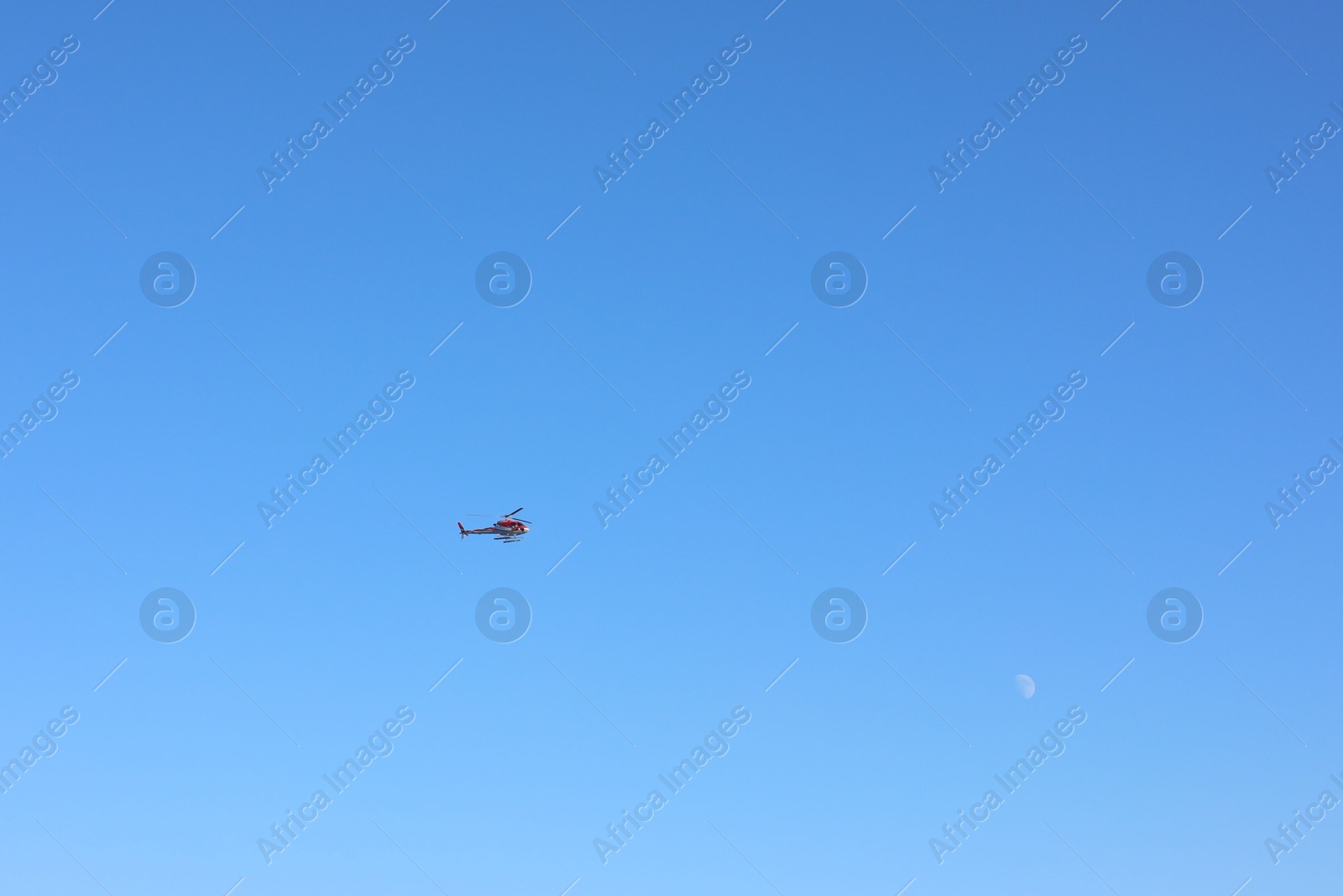 Photo of Modern helicopter flying in clear blue sky on sunny day