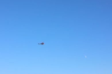 Photo of Modern helicopter flying in clear blue sky on sunny day