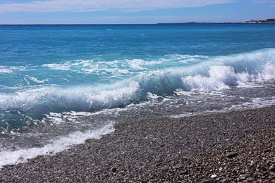 Photo of Beautiful view of wavy sea, city and pebbles on beach
